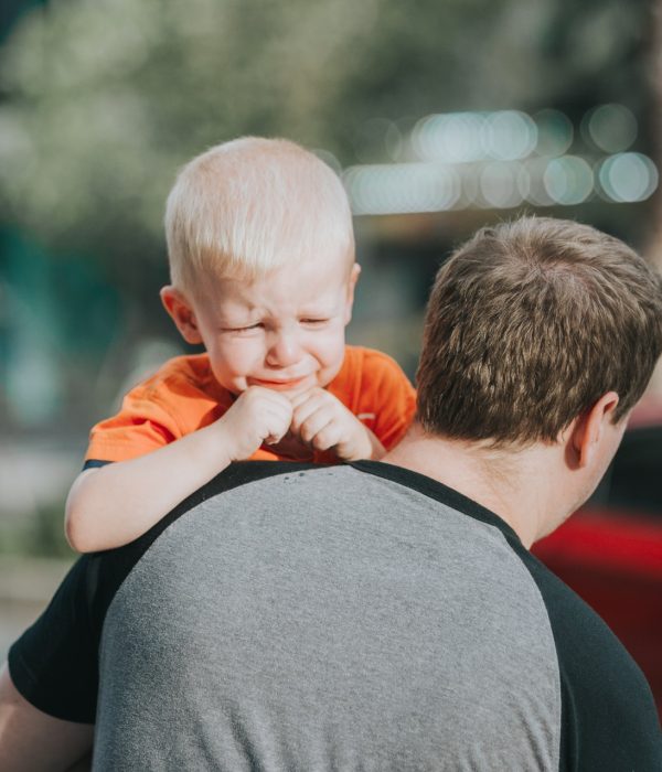 Enfant qui pleure dans les bras de son père